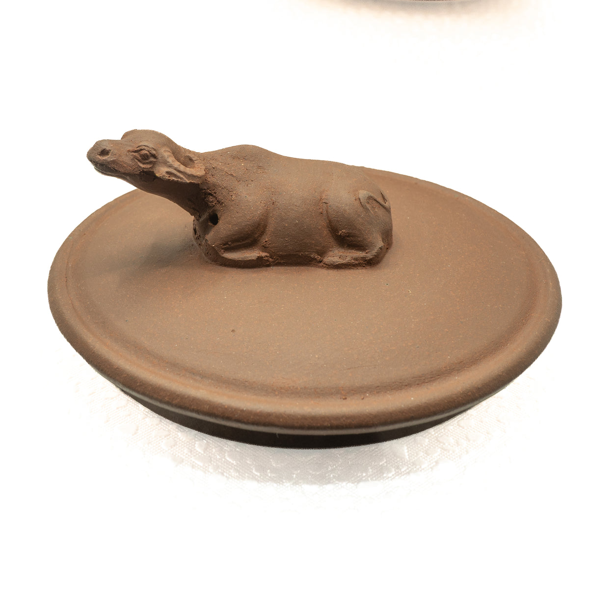 Close-up macro view of an authentic vintage Yixing Zisha teapot lid featuring a hand-sculpted resting water buffalo finial.