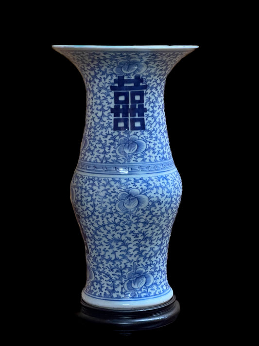An antique Chinese blue and white porcelain yen yen vase hand-painted with a dense scrolling sweet pea vine motif and a prominent double happiness calligraphy symbol on a wooden pedestal.