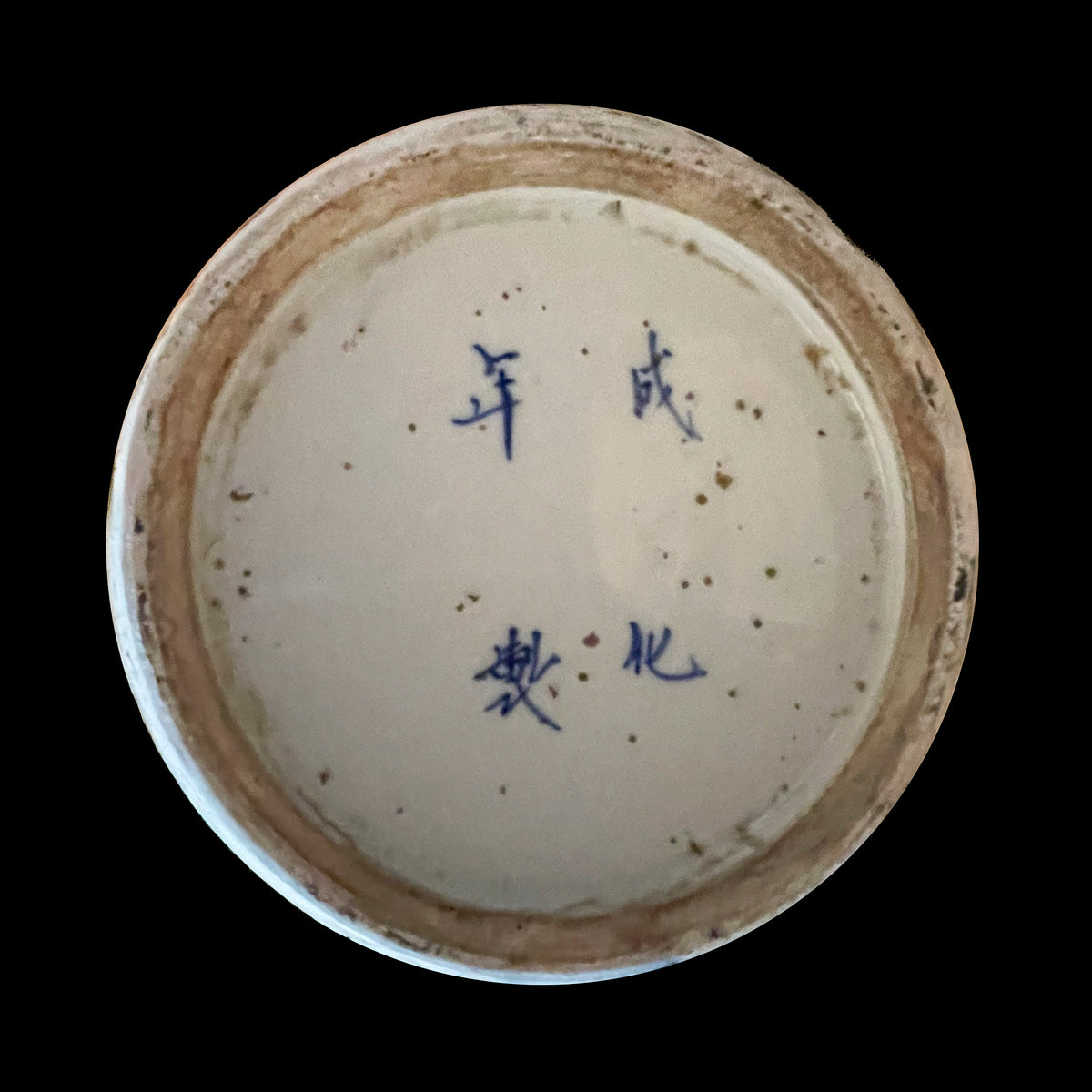 A close up macro view of an antique Chinese porcelain vase base showcasing a hand painted underglaze blue four character Chenghua Nian Zhi mark within a circular unglazed foot rim.