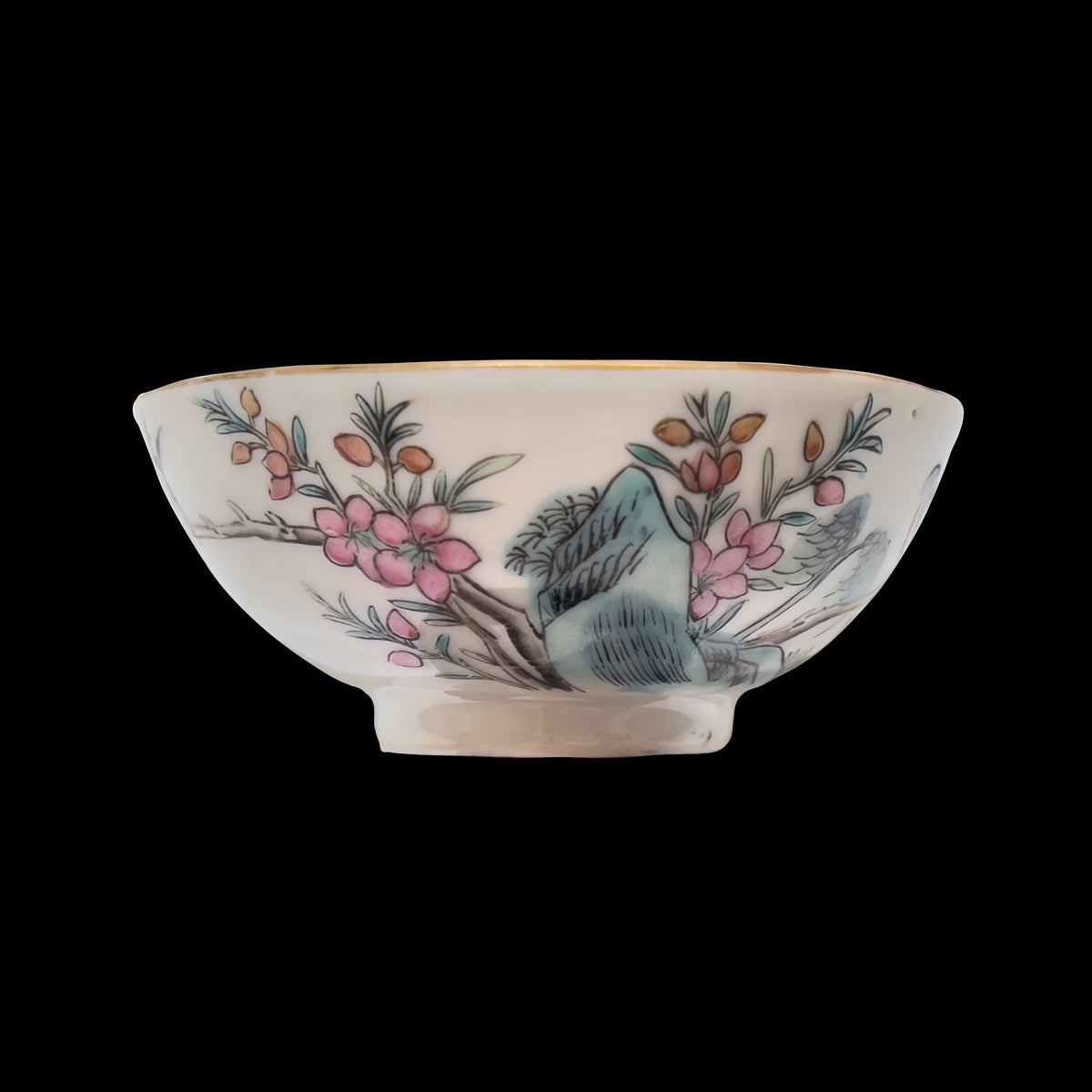 A centered profile studio shot of an antique Chinese famille rose porcelain 3.5 inch wine cup showing hand-enameled pink plum blossoms over blue rockwork with a gilded gold rim.
