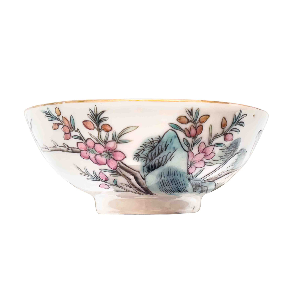 A centered profile studio shot of an antique Chinese famille rose porcelain 3.5 inch wine cup showing hand-enameled pink plum blossoms over blue rockwork with a gilded gold rim.
