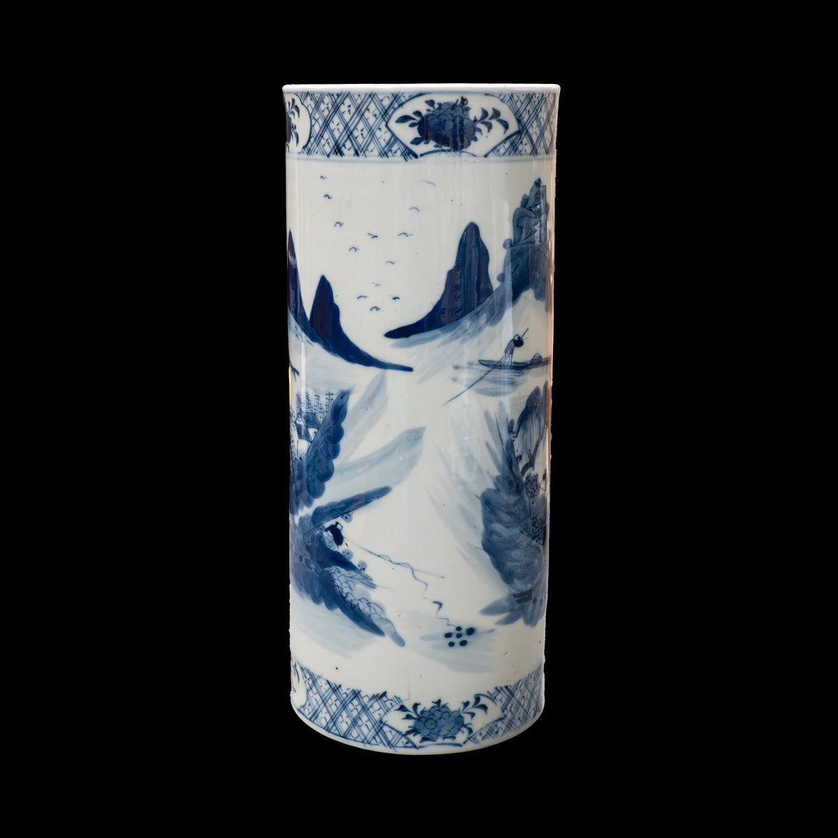 The reverse side of a cylindrical 19th-century Chinese blue and white porcelain vase against a black background. The painting features an open, minimalist composition depicting a lone fisherman steering a small boat on a tranquil river, flanked by sharp mountain crags. A flock of distant birds flies across the white porcelain sky.
