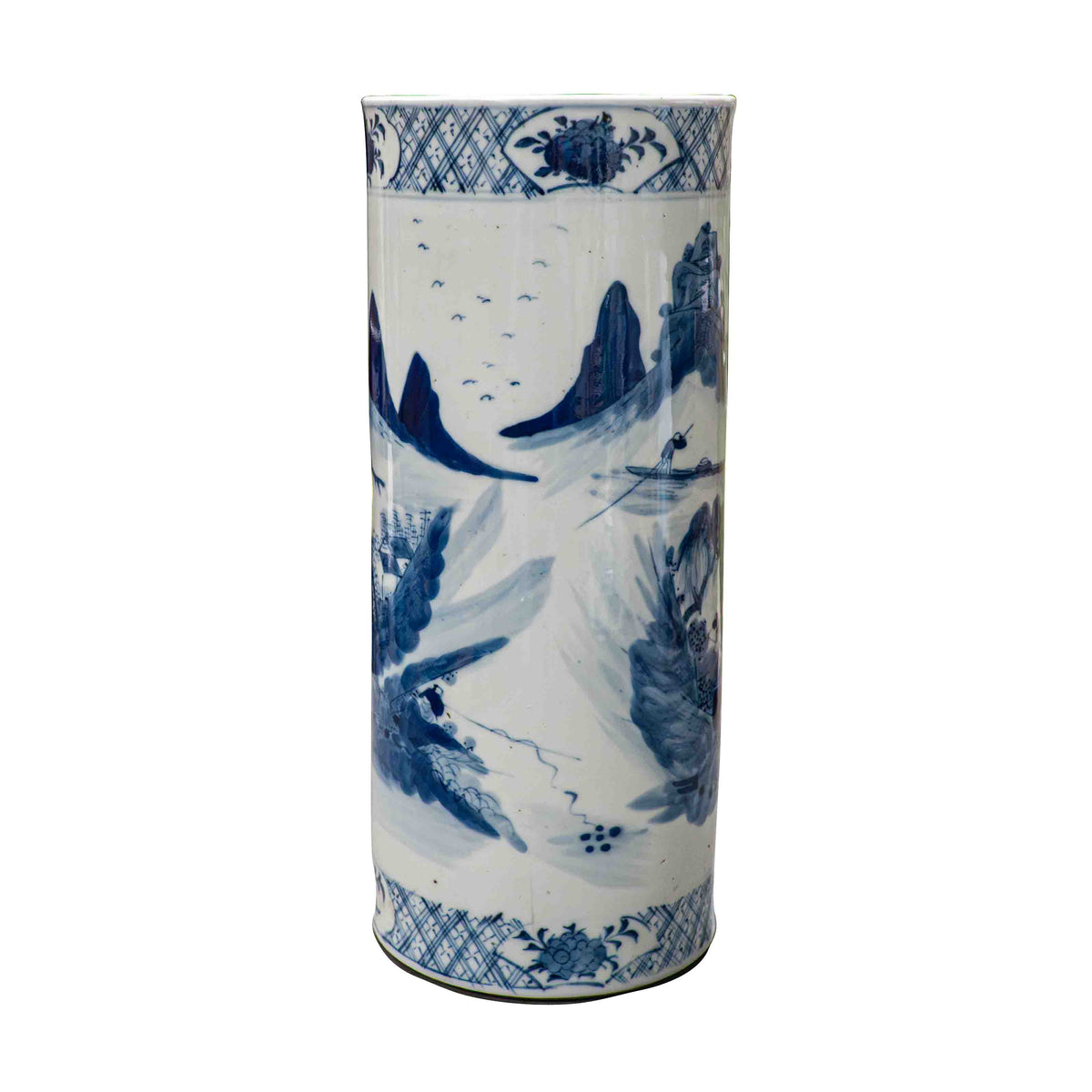 The reverse side of a cylindrical 19th-century Chinese blue and white porcelain vase against a black background. The painting features an open, minimalist composition depicting a lone fisherman steering a small boat on a tranquil river, flanked by sharp mountain crags. A flock of distant birds flies across the white porcelain sky.