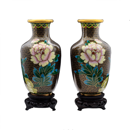 A pair of vintage Chinese cloisonné enamel baluster vases featuring hand-enamelled pink blooming peony blossoms over a black cloud pattern ground on carved wooden stands.
