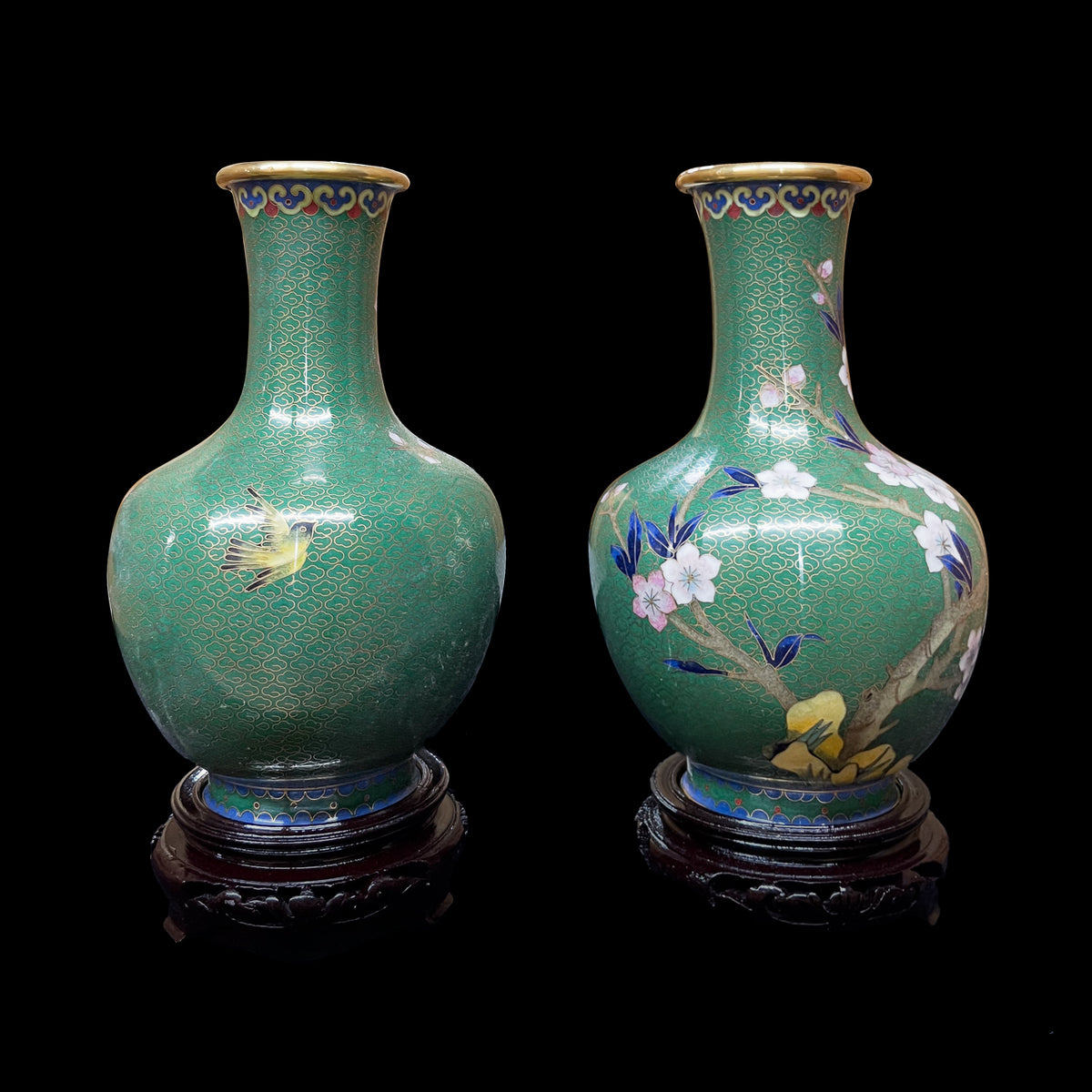 Vintage Chinese cloisonne enamel emerald green vases on tier stands, showing side-by-side front and back profiles decorated with traditional plum blossoms, leafy branches, and a golden bird in flight.